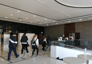 Grupa uczniów idzie przez hall hotelu do sali konferencyjnej